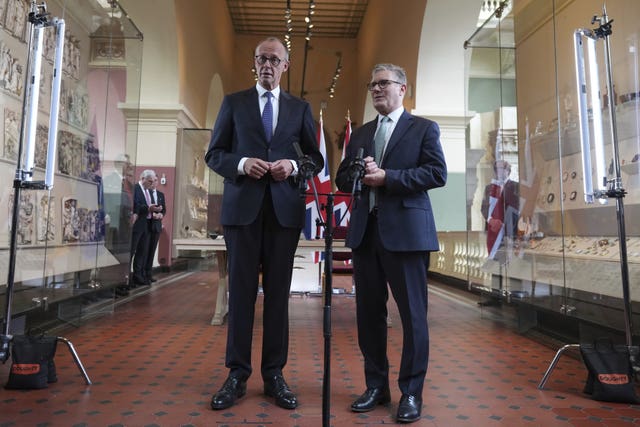 Friedrich Merz in front of a microphone at the V&A Museum in London with Sir Keir Starmer
