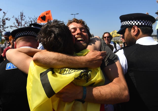 Extinction Rebellion demonstrators hug across a police cordon on Waterloo Bridge (Victoria Jones/PA)