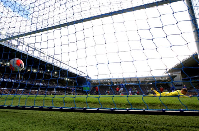 Jordan Pickford lies prone on the ground as Bruno Fernandes' shot hits the net