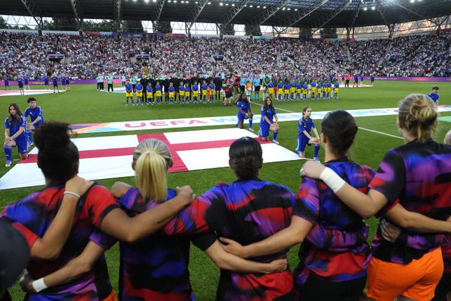 England’s Jess Carter, centre, facing away, and team-mates stand with linked arms ahead of the Euro 2025 semi-final against Italy