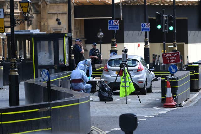 Forensic officers by the car that crashed into security barriers outside the Houses of Parliament