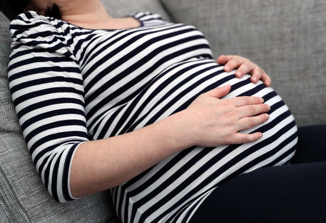 A pregnant woman holds her stomach 