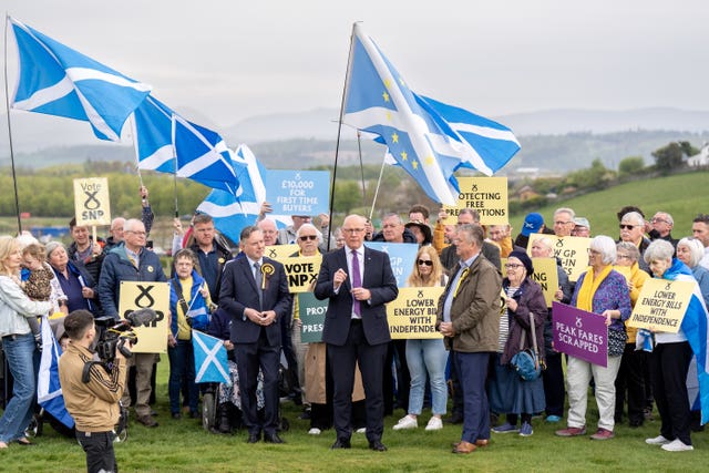 John Swinney smiling in a large group of SNP supporters outside