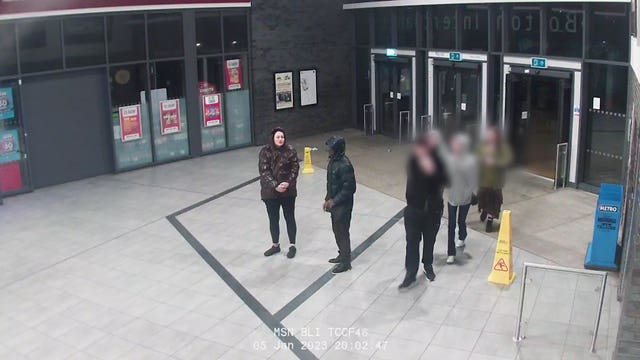 Grainy still taken from CCTV footage showing a group of people by the doors to a bus station
