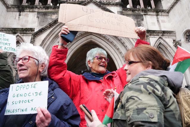 Palestine Action protesters celebrate while waving signs