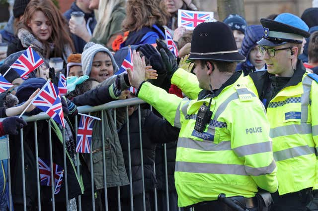 Police officers high-five children as they await the arrival of the Duke and Duchess of Cambridge in Coventry