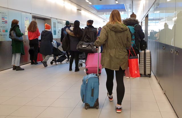 People queue for a shuttle train at Gatwick Airport