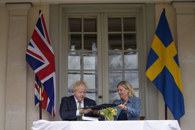 Boris Johnson and Swedish prime minister Magdalena Andersson exchange files as they sign the security assurance