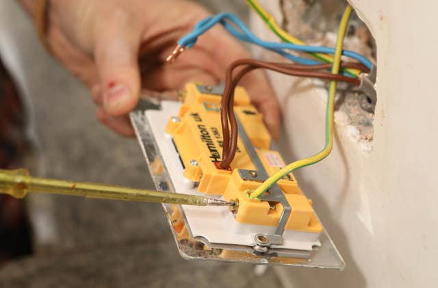 Richard Burr removing an old socket before fitting a USB plug into a wall