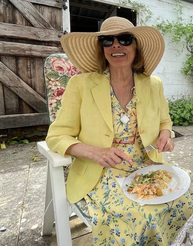 Dame Esther Rantzen smiling while seated outside, eating lunch