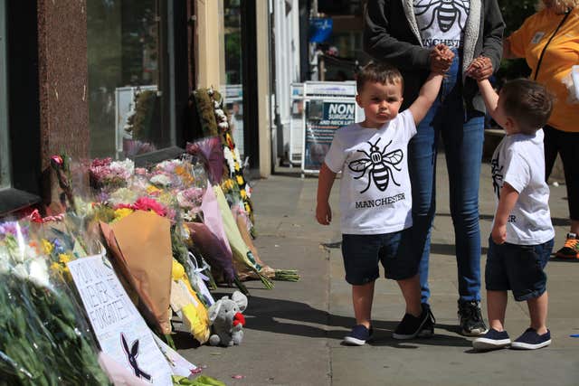 A woman and two young boys view tributes ahead of the Manchester Arena National Service of Commemoration at Manchester Cathedral (Peter Byre/PA)