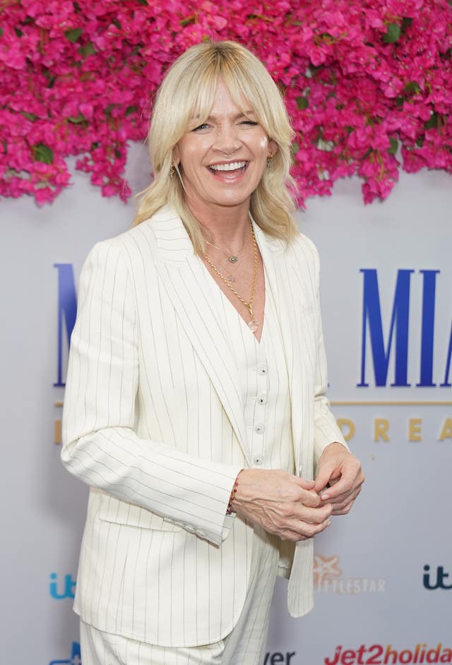 Zoe Ball smiling wearing a white suit