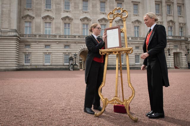 Senior footman Olivia Smith (left) and footman Heather McDonald place a notice on an easel in the forecourt of Buckingham Palace formally announce the birth of the baby boy (Stefan Rousseau/PA)