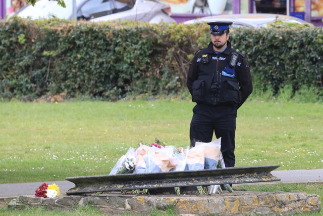 A PCSO looks at flowers and messages left in Aylesham, Kent, for PCSO Julia James