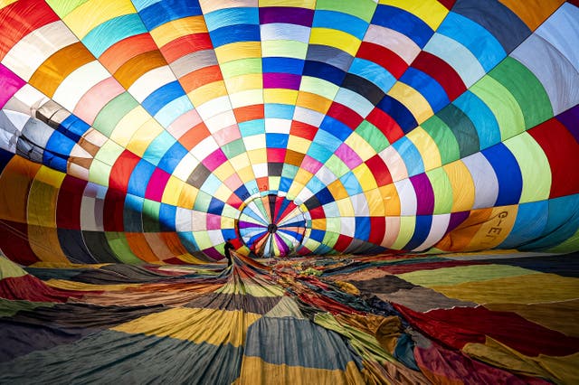 A pilot checking internal rigging inside one colourful balloon