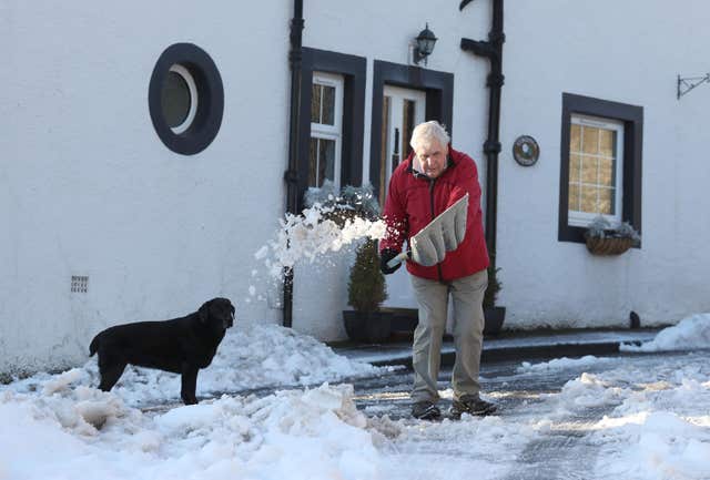 John Hutcheson with dog Heidi clears snow in Tower Road, Darnick (Andrew Milligan/PA)