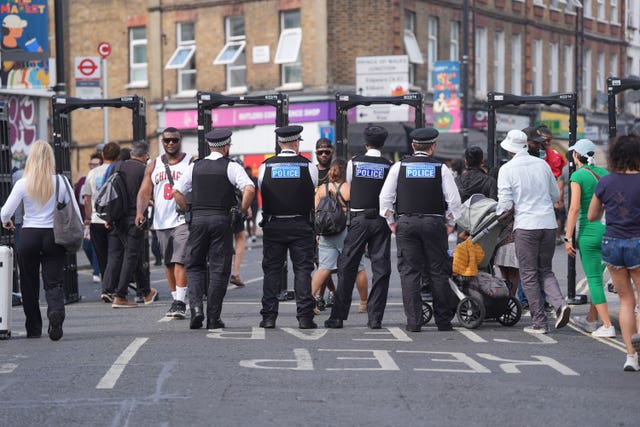 Police officers stand by portable walk through metal detectors set up for use during the the Notting Hill Carnival in London