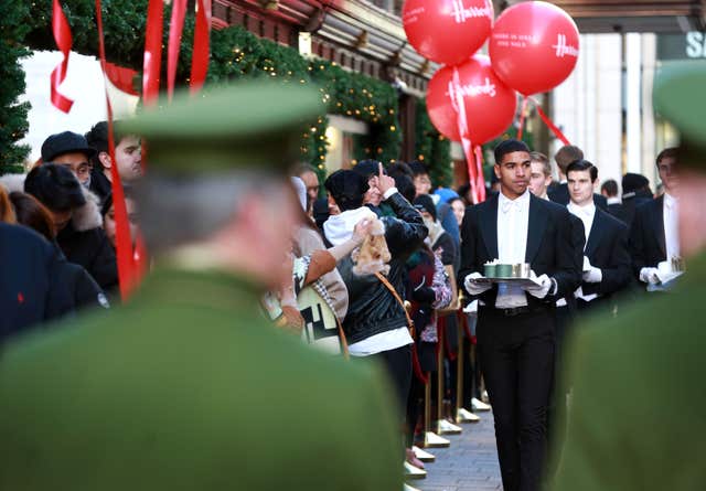 Harrods butlers serve drinks to shoppers as they queue outside the store in Knightsbridge, London ahead of the launch of its winter sale (Matt Alexander/PA)