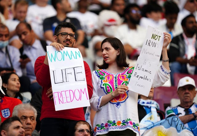 Iran fans in the stands hold up signs of protest