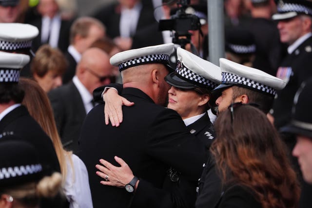 Police officers hug each other before the funeral of Pc Matthew Blades