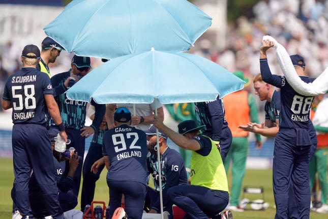 England players shelter under umbrellas as they take a drinks break and use ice to cool down