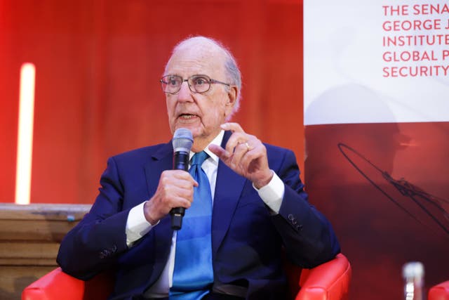 Senator George Mitchell speaks into a microphone while seated