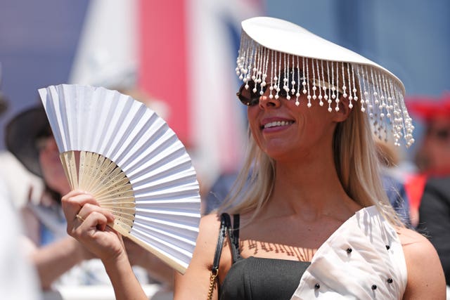 A racegoer fans herself in the hot weather on day four of Royal Ascot at Ascot Racecourse, Berkshire