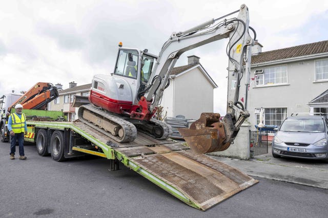 A mechanical digger is unloaded from a lorry