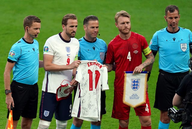 Harry Kane, hands a shirt with Christian Eriksen's name on it to Denmark's Simon Kjaer before the semi-final 