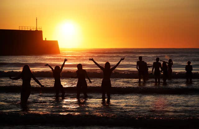 Swimmers had a great view of the stunning sunrise as they braved the cold (Jane Barlow/PA)