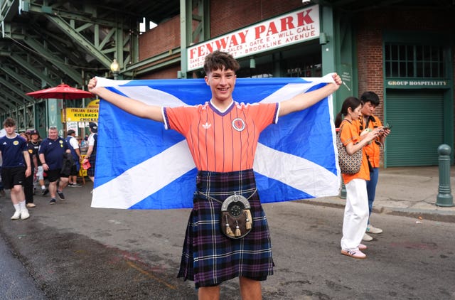 A Scotland fan smiling while holding up a flag
