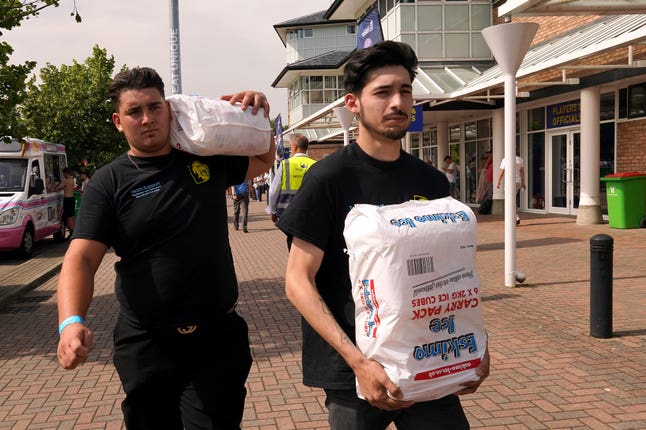 Staff carry bags of ice cubes into the ground