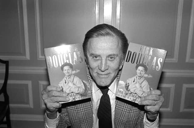 Hollywood actor Kirk Douglas poses with copies of his autobiography The Ragman’s Son in 1988