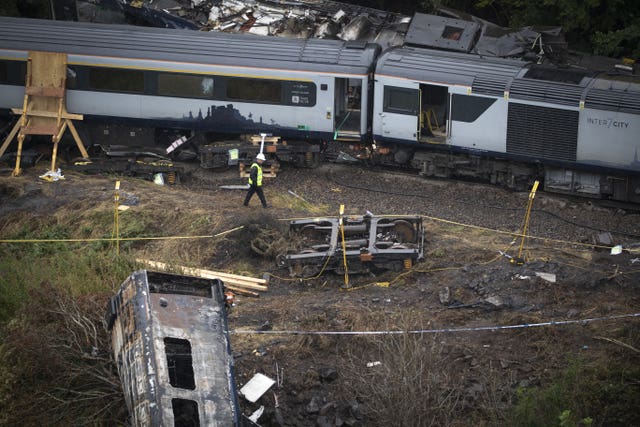 Derailed train carriages, including one which shows signs of fire and is on an embankment away from the rest of the train