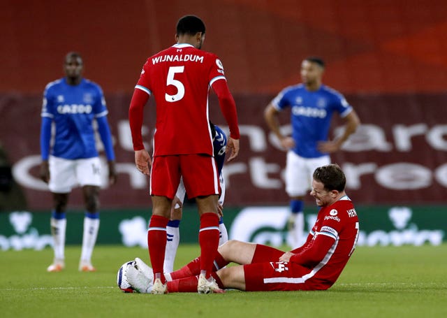 Liverpool captain Jordan Henderson sits on the pitch injured watched by Georginio Wijnaldum