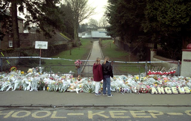 Two children stand in front of the flower tribute to the massacre that happened at Dunblane Primary School (Stefan Rousseau/PA)