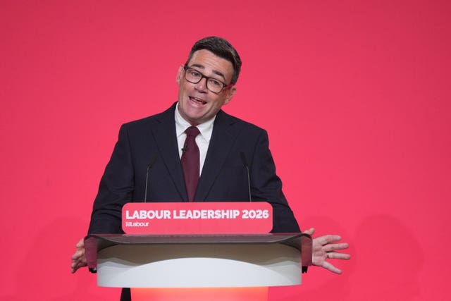 Andy Burnham, wearing a shirt and tie, giving a speech in front of a red backdrop after being named as the new leader of the Labour Party