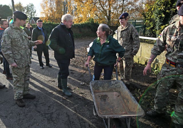 Boris Johnson talks with a local woman pushing a wheelbarrow during a visit to Stainforth