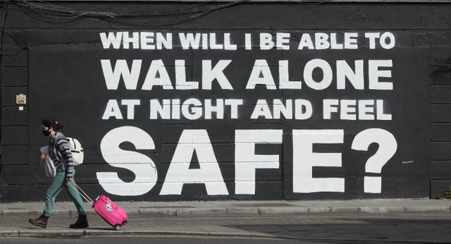 A member of the public walks past a mural asks: ‘When will I be able to walk alone at night and feel safe?’
