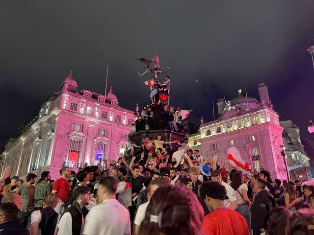 England football fans climb the statue of Eros in Piccadilly Circus, central London