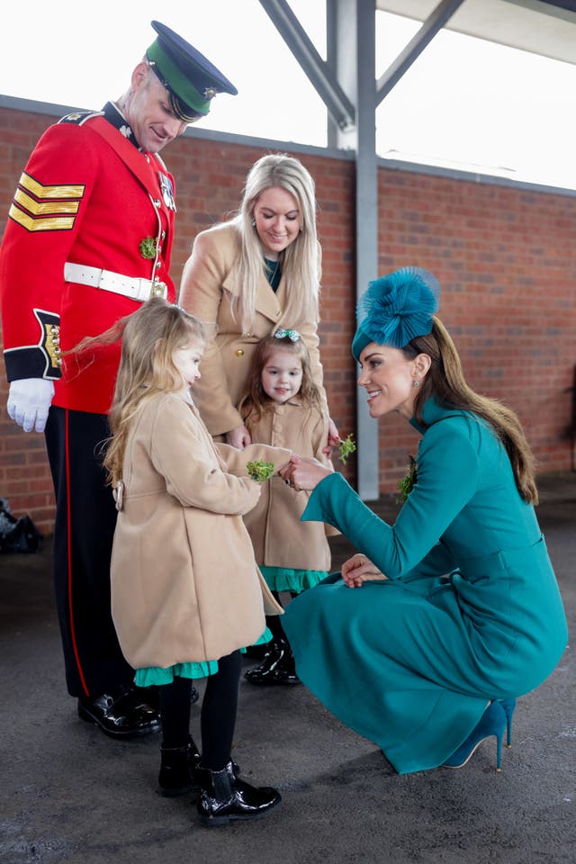 The Princess of Wales presents the traditional sprigs of shamrock to an officer's children during a visit to the 1st Battalion Irish Guards for the St Patrick’s Day Parade, at Mons Barracks in Aldershot