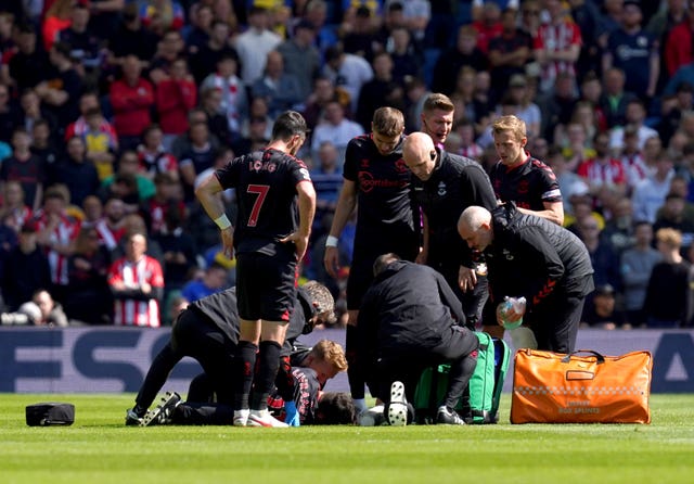 Tino Livramento is receiving medical attention after suffering a serious knee injury during Southampton's match at Brighton in April 2022