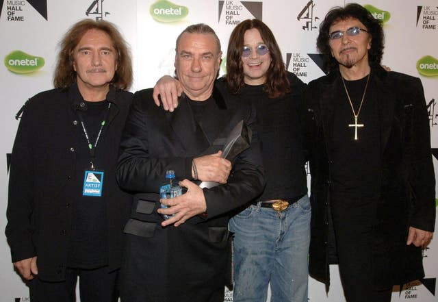 Four members of Black Sabbath smiling while posing for a photo