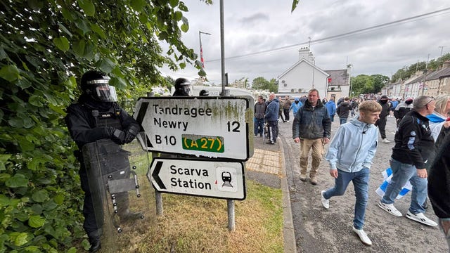 PSNI officers in riot gear watch as a protest march passes by