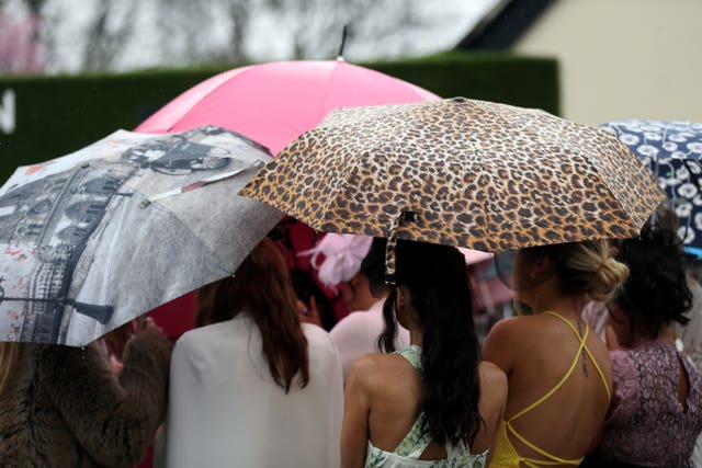 Racegoers accessorised with colourful umbrellas (David Davies/PA)