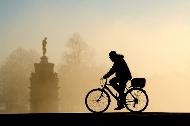 A person cycling in Bushy Park in London at dusk in winter