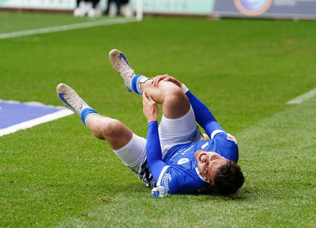 Ollie Tanner holds his leg in pain as he lies on the floor