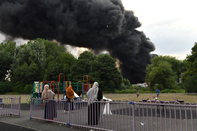 People watch on as smoke billows from a severe blaze on an industrial estate in Birmingham