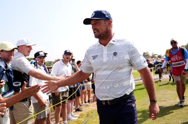 Bryson DeChambeau embraces spectators on his way to the second tee