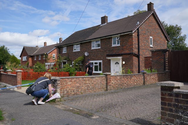 A person leaves flowers outside a property in Woking where Sara was found dead (PA)